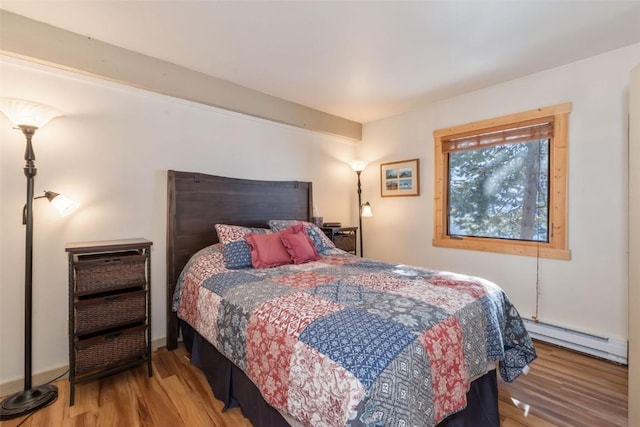 bedroom with a baseboard radiator and wood finished floors