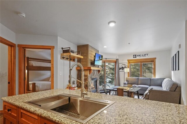 kitchen featuring light stone countertops, a stone fireplace, and sink