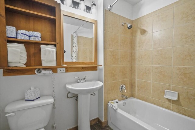 full bathroom featuring sink, shower / bathtub combination with curtain, and toilet