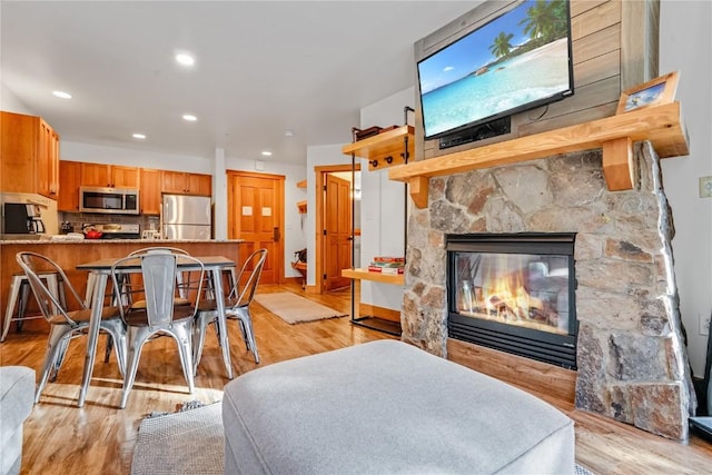 dining area with light hardwood / wood-style floors and a stone fireplace