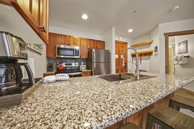 kitchen with decorative backsplash, sink, a kitchen bar, and stainless steel appliances