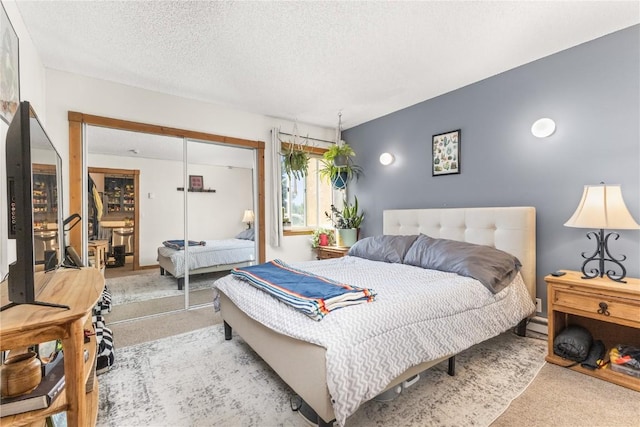 carpeted bedroom with a textured ceiling and a closet