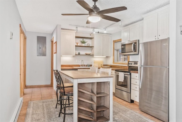 kitchen with appliances with stainless steel finishes, baseboard heating, ceiling fan, electric panel, and white cabinetry