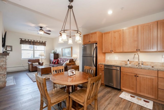 kitchen featuring pendant lighting, ceiling fan with notable chandelier, sink, light stone countertops, and appliances with stainless steel finishes