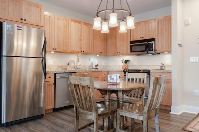 kitchen with light stone countertops, light brown cabinetry, hanging light fixtures, and appliances with stainless steel finishes