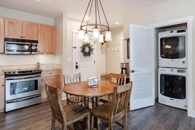 dining area featuring dark wood-type flooring, stacked washer / drying machine, and a notable chandelier