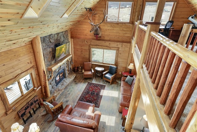 living room featuring hardwood / wood-style floors, wood walls, high vaulted ceiling, a skylight, and wood ceiling