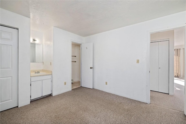 unfurnished bedroom featuring light carpet, a textured ceiling, and ensuite bathroom