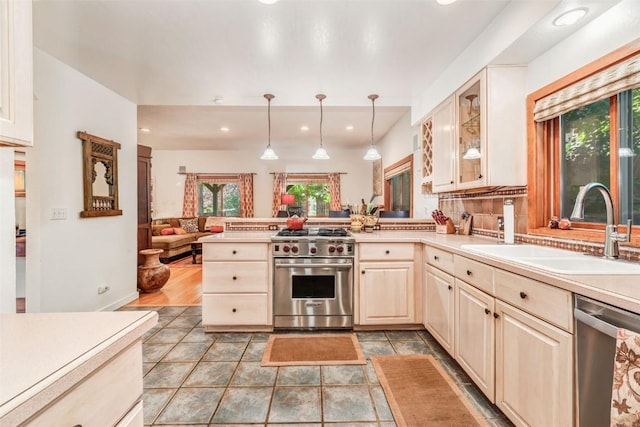 kitchen featuring sink, tasteful backsplash, decorative light fixtures, appliances with stainless steel finishes, and kitchen peninsula