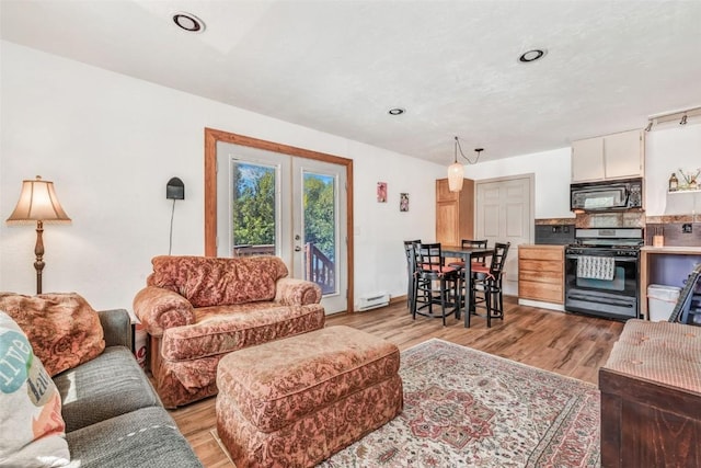 living room with french doors, a baseboard heating unit, and light hardwood / wood-style flooring