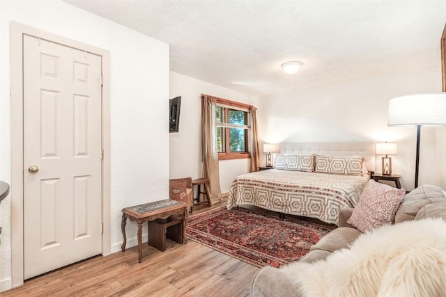 bedroom with a textured ceiling and light wood-type flooring