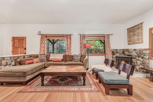 living room featuring a stone fireplace, plenty of natural light, and hardwood / wood-style flooring