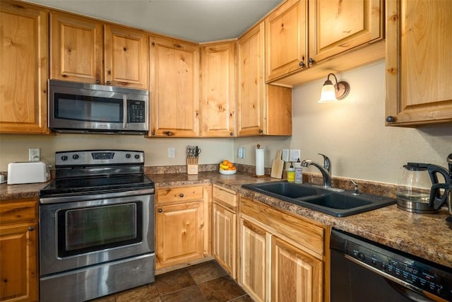 kitchen with dark countertops, appliances with stainless steel finishes, and a sink