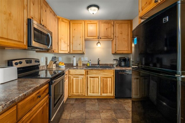 kitchen with a sink, stone finish flooring, dark countertops, and black appliances