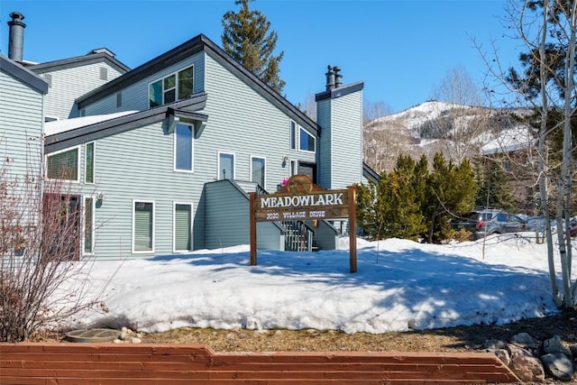 snow covered back of property featuring a mountain view