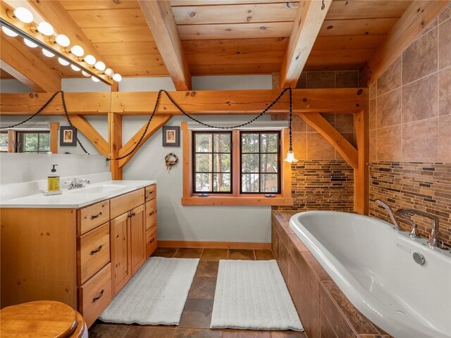 bathroom with vanity, beam ceiling, a wealth of natural light, and tiled tub