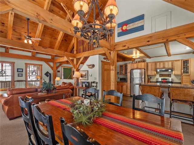 dining space with beam ceiling, high vaulted ceiling, light colored carpet, wood ceiling, and ceiling fan with notable chandelier