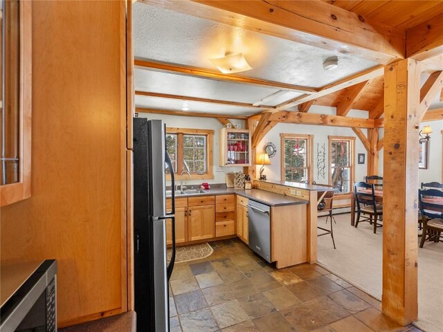 kitchen with dishwasher, sink, kitchen peninsula, a kitchen bar, and black refrigerator