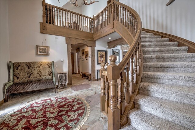 stairs featuring a high ceiling and a chandelier