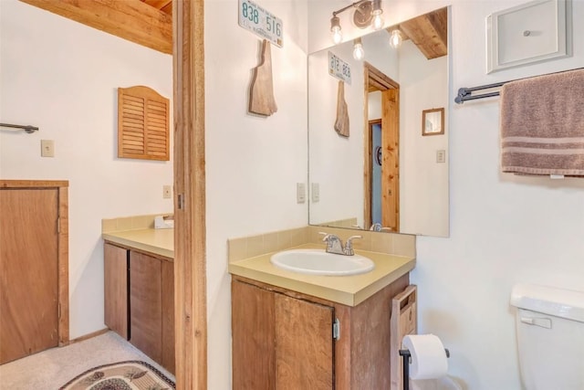 bathroom with vanity, beam ceiling, and toilet