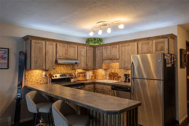 kitchen with tile countertops, sink, a kitchen bar, kitchen peninsula, and stainless steel appliances