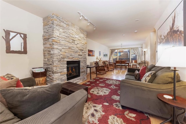 living room featuring track lighting, a fireplace, and light hardwood / wood-style flooring