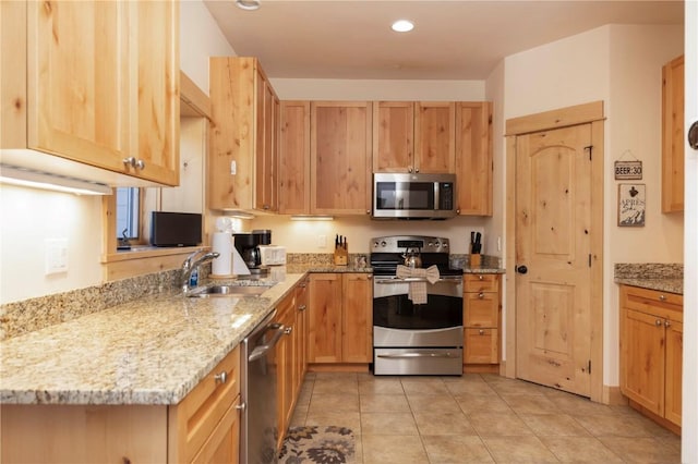 kitchen featuring stainless steel appliances, light brown cabinetry, sink, light stone counters, and light tile patterned floors