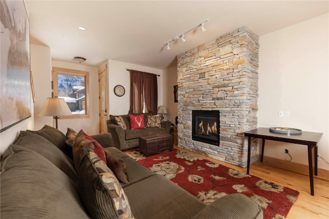 living room featuring rail lighting, a fireplace, and light hardwood / wood-style flooring