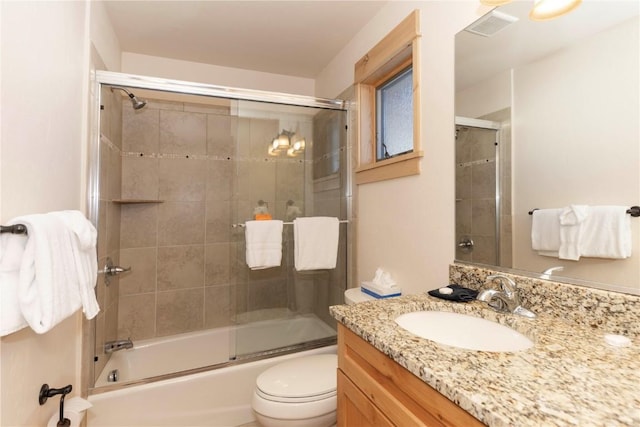 full bathroom featuring toilet, vanity, and shower / bath combination with glass door