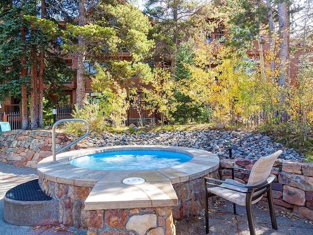 view of pool featuring fence and an in ground hot tub