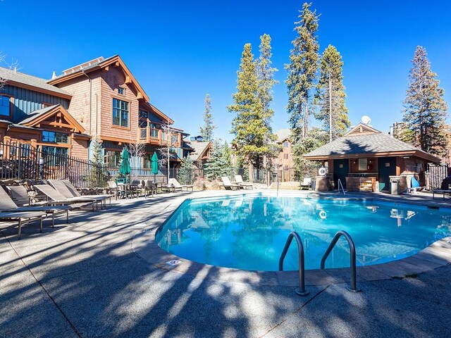 community pool with a patio area and fence