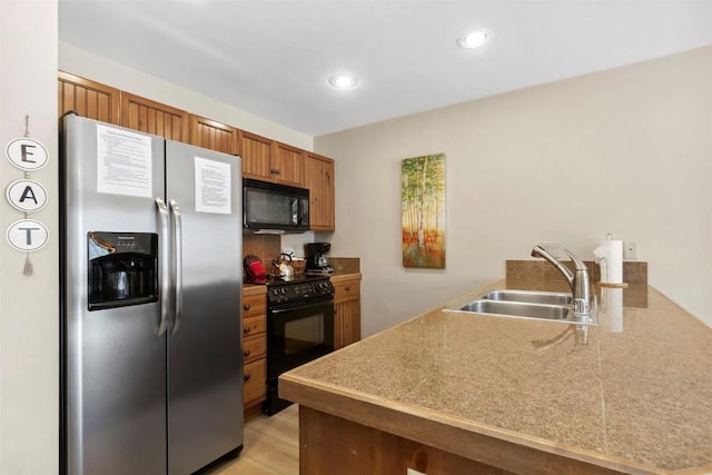 kitchen with recessed lighting, a peninsula, a sink, black appliances, and brown cabinetry