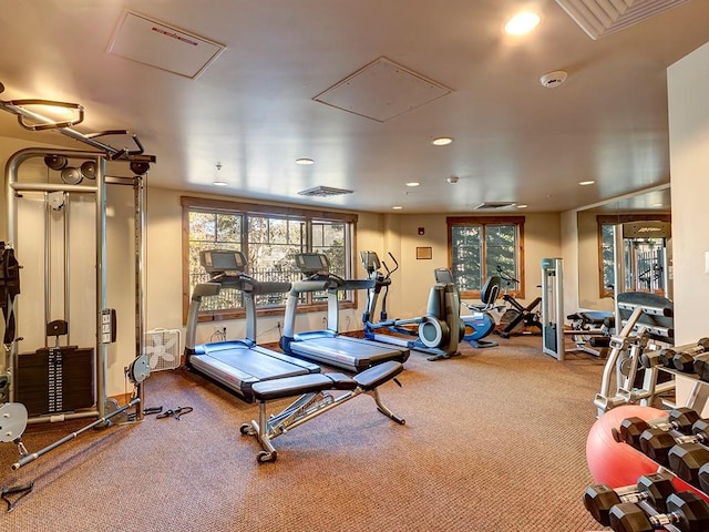 gym featuring attic access, a wealth of natural light, visible vents, and recessed lighting