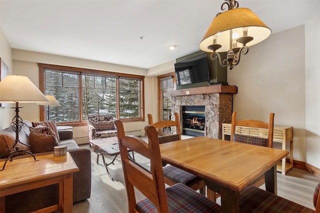 dining area with a stone fireplace, wood finished floors, and baseboards