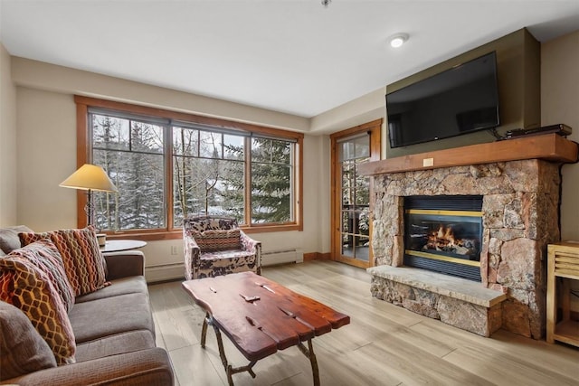 living area with a baseboard radiator, a stone fireplace, and wood finished floors