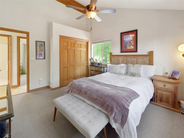 bedroom with ceiling fan, a closet, light carpet, and vaulted ceiling