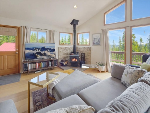 interior space with wood-type flooring, a wood stove, and high vaulted ceiling