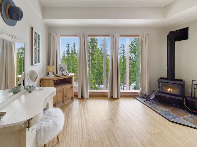 sitting room with a healthy amount of sunlight, light wood-type flooring, and a wood stove