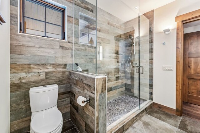 bathroom featuring toilet and a shower with shower door