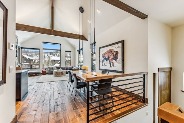 dining area with beam ceiling, hardwood / wood-style floors, and high vaulted ceiling