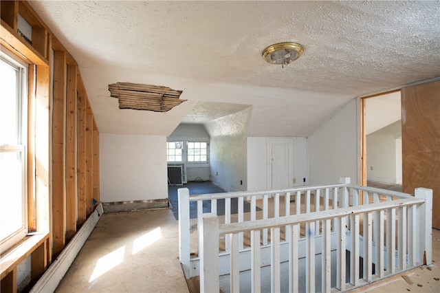 hall with a textured ceiling and vaulted ceiling