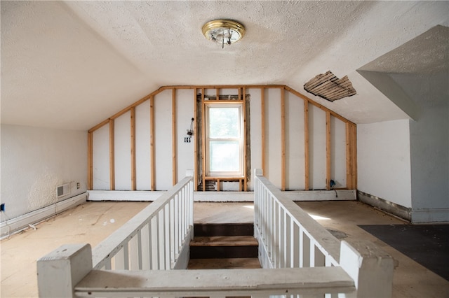 stairway with lofted ceiling and a textured ceiling