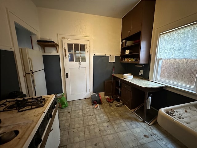 kitchen with light tile flooring, dark brown cabinetry, and white fridge