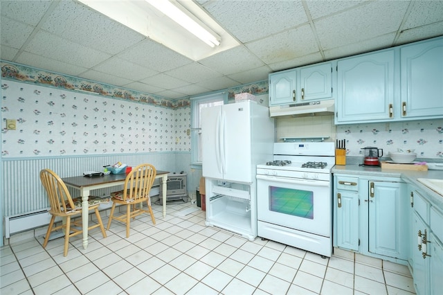 kitchen with light tile flooring, a paneled ceiling, and white appliances