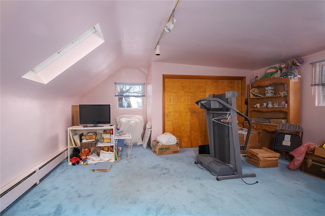 interior space featuring vaulted ceiling with skylight, track lighting, light colored carpet, and a baseboard radiator