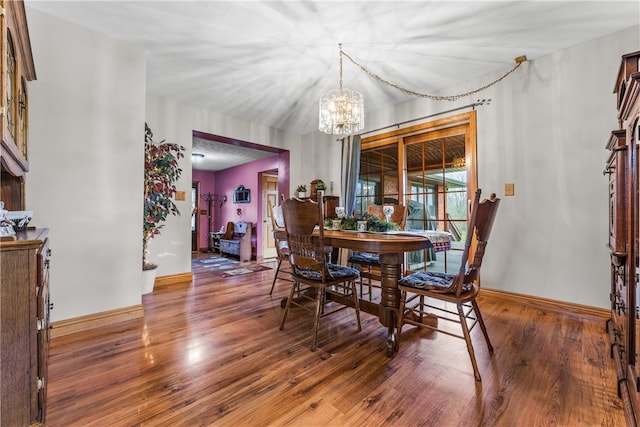 dining space with dark hardwood / wood-style floors and a chandelier