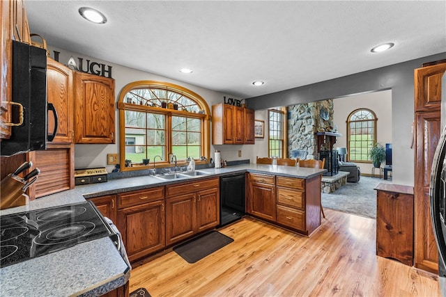 kitchen with light colored carpet, kitchen peninsula, black dishwasher, a fireplace, and sink