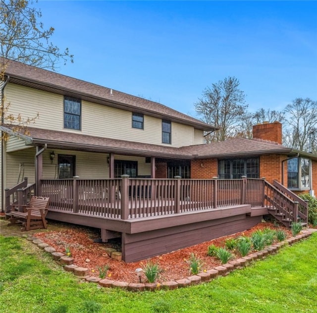 rear view of house with a wooden deck and a lawn