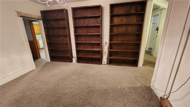 unfurnished bedroom featuring light carpet and a notable chandelier