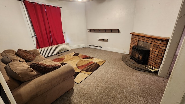 living room with dark colored carpet, radiator, a fireplace, and a wood stove